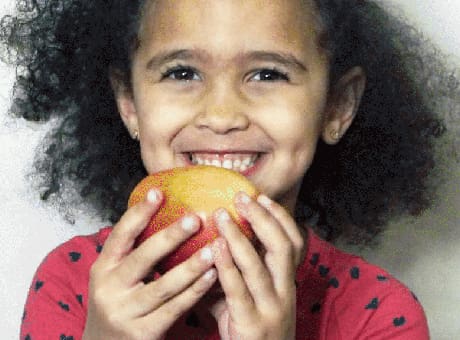 Young child holding an apple and smiling