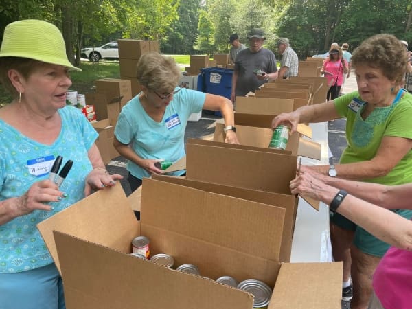 Three older women going through boxes of canned food