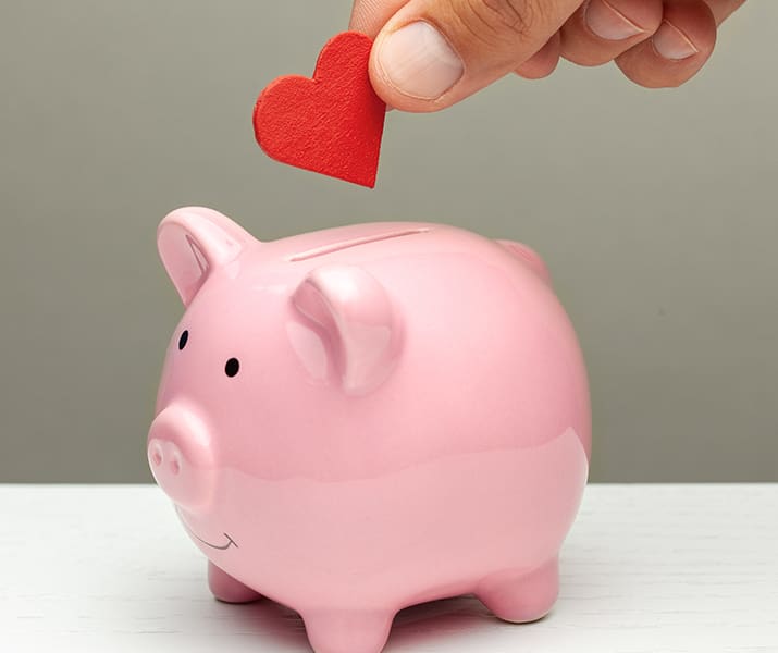 Putting a heart shaped paper in a piggy bank