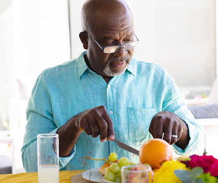 Older man cutting food at dinner table