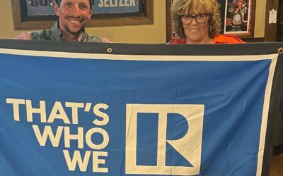 Two realtors holding the Anne Arundel County Association of REALTORS flag.