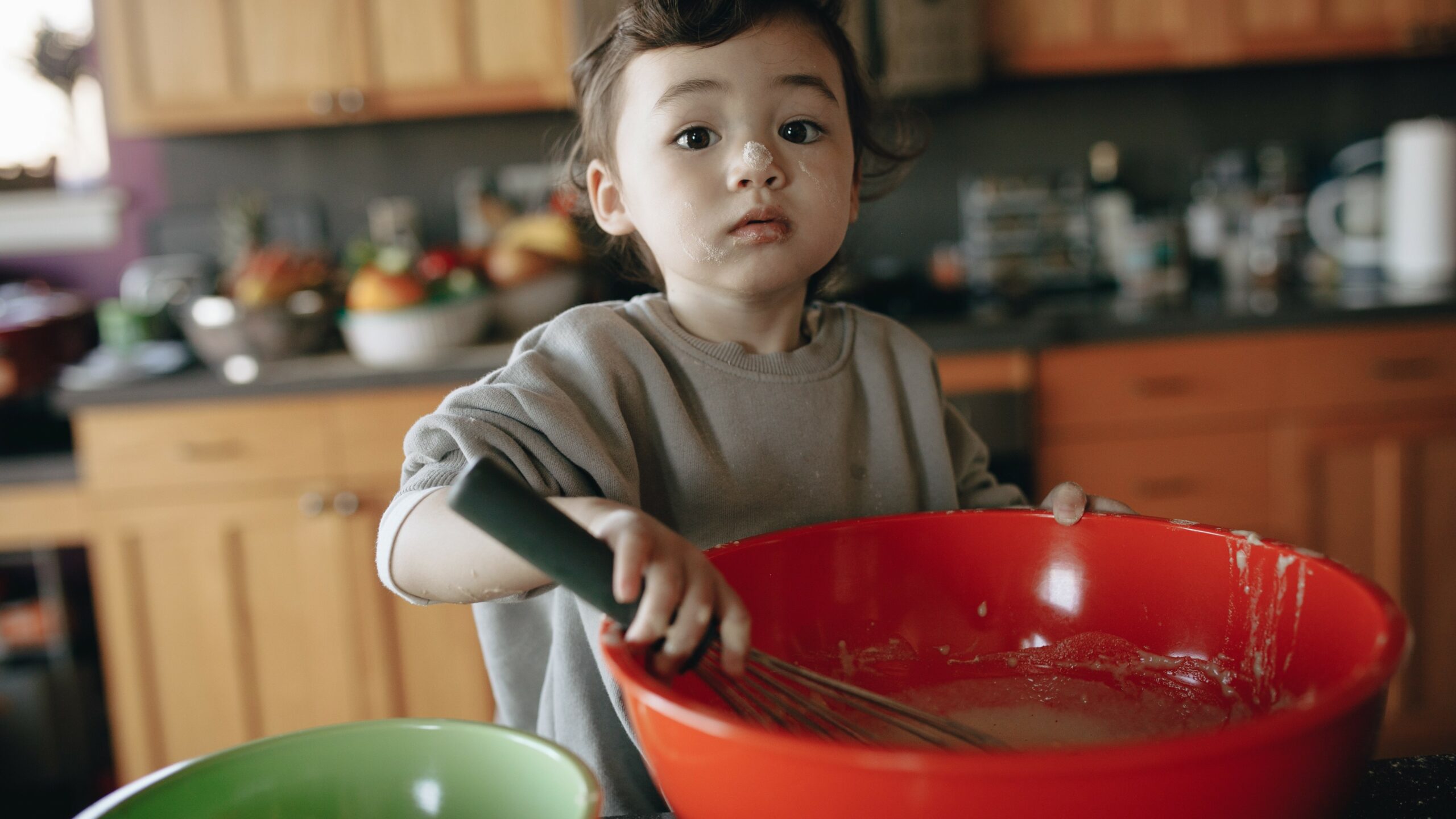 Young kid stirring batter and helping bake.